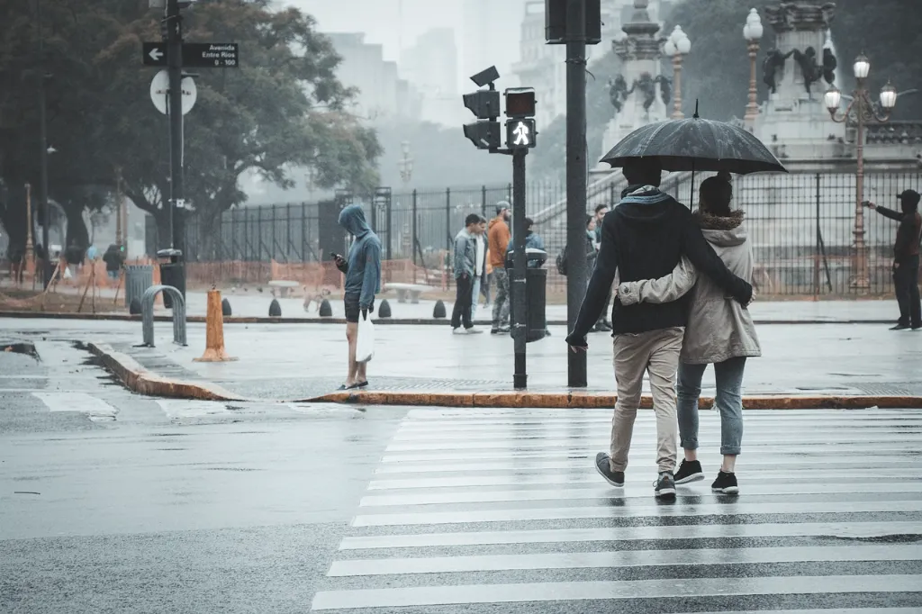 A couple crossing the street when it's raining.